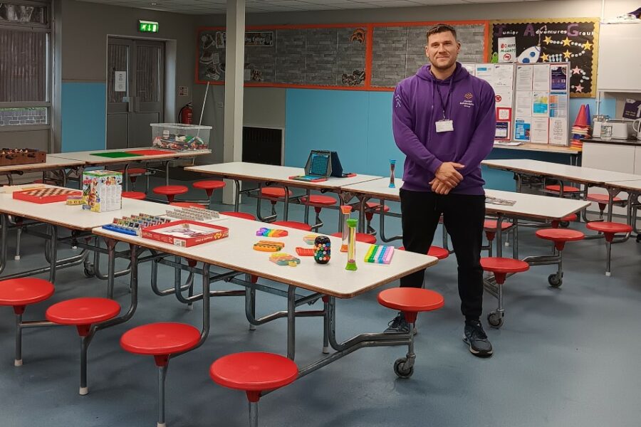 A man stood in a classroom with games and toys on a table