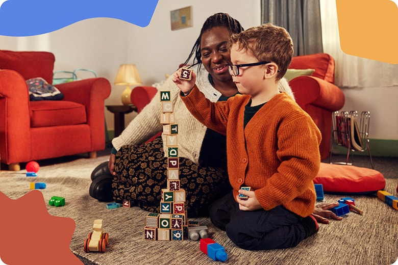 A woman and a child playing with blocks in a living room.