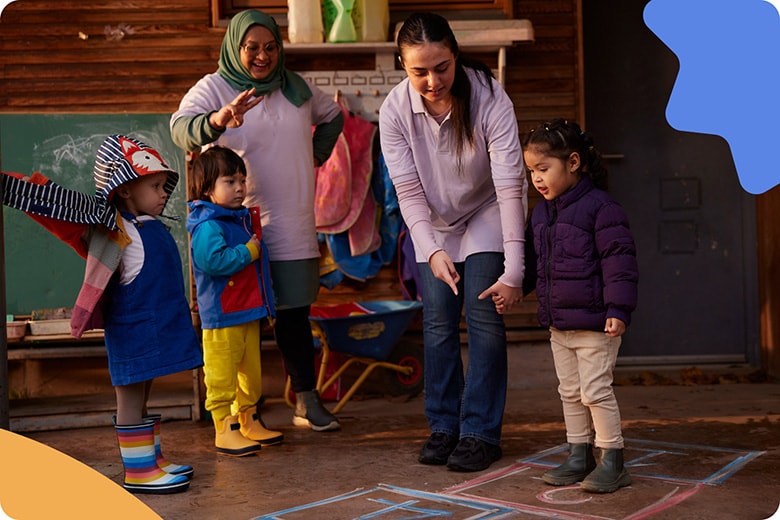 Two women and 3 children playing hopscotch