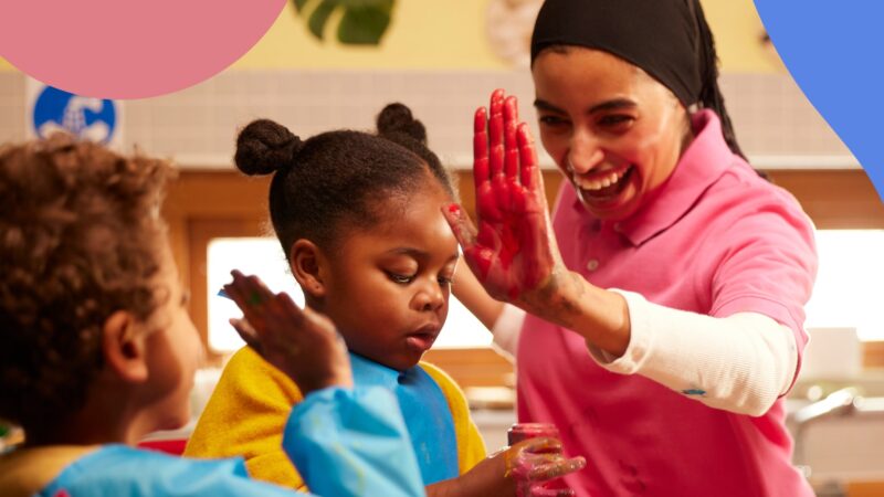 A woman with stained hands high-fives a child.