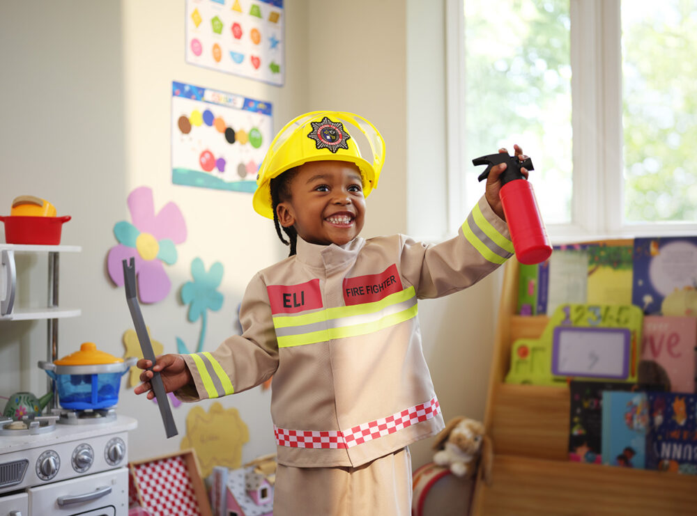 Smiling young boy dressed as a firefighter, playing in a nursery room